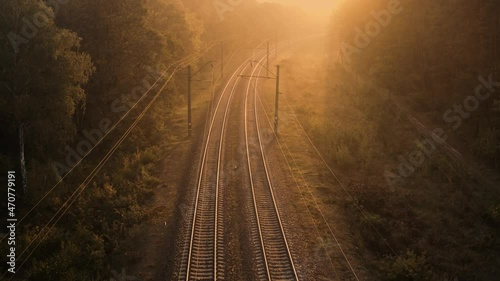 Railway track in a coniferous forest at dawn. View from the drone.