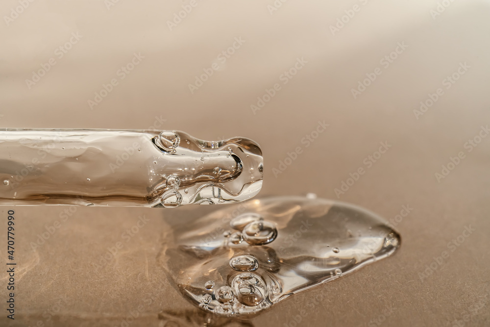 The texture of serum or oil with a pipette on a beige background.