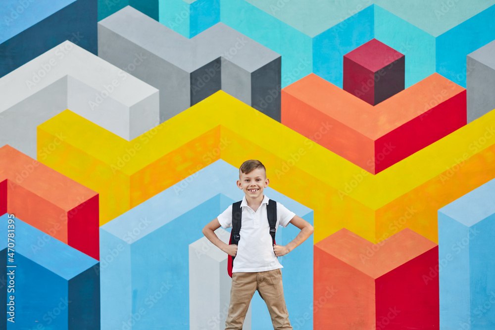 Content schoolboy with backpack against bright wall Content schoolboy with backpack against bright wall