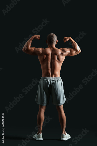 Male bodybuilder on dark background, back view