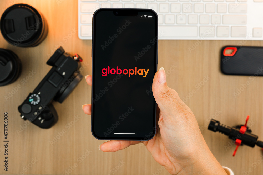 Female Hand Holding A Smartphone IPhone 13 Pro With Globoplay App On female-hand-holding-a-smartphone-iphone-13-pro-with-globoplay-app-on