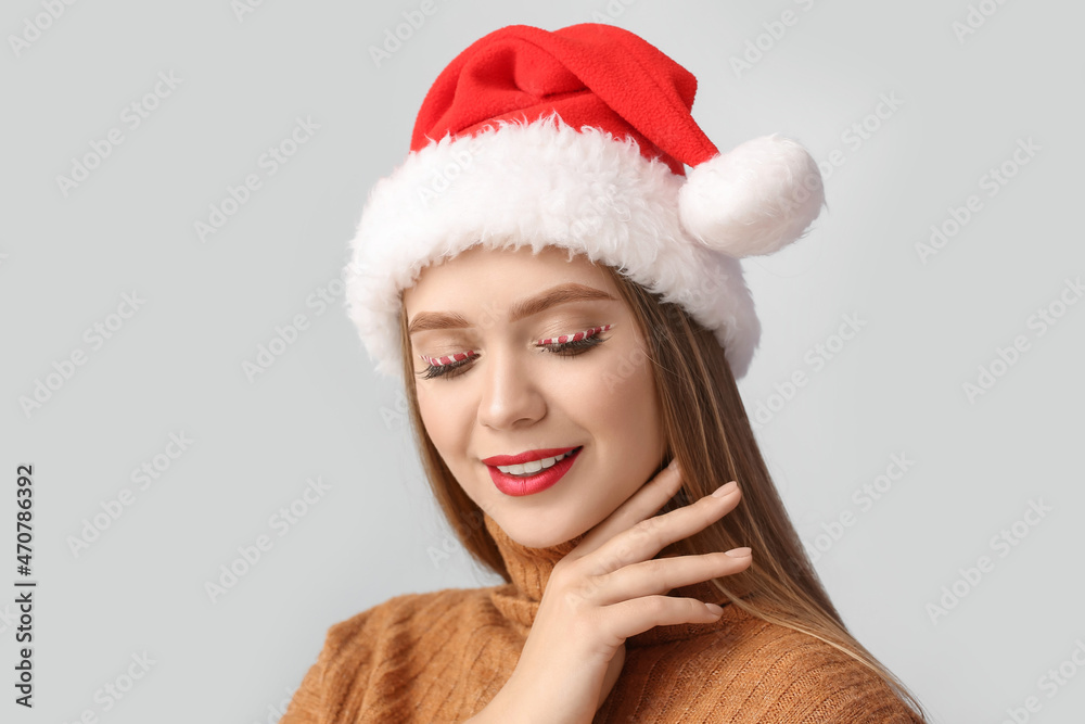 Beautiful young woman in Santa hat on grey background Beautiful young woman in Santa hat on grey background