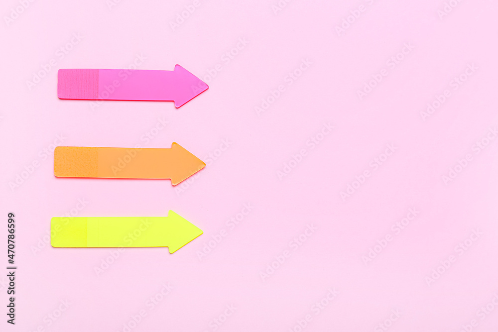 Colorful sticky notes in shape of arrows on pink background Colorful sticky notes in shape of arrows on pink background