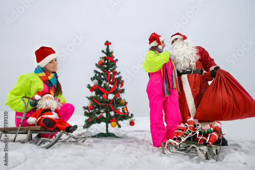 Two girls with Santa Claus decking up the Christmas tree at snow