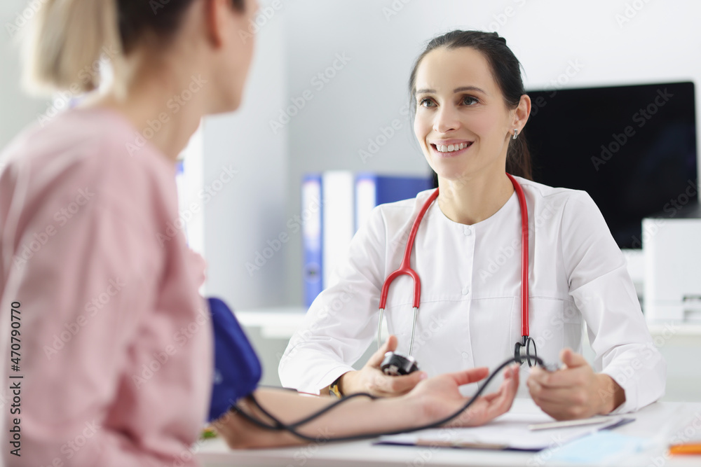 Smiling doctor measuring patients blood pressure with tonometer tool and talk Smiling doctor measuring patients blood pressure with tonometer tool and talk