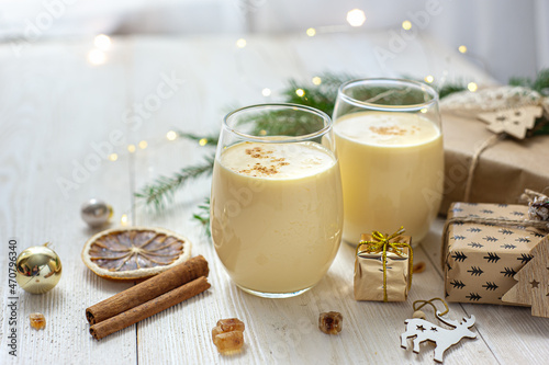 Two glasses of eggnog on a white wooden table next to the Christmas presents. Sweet egg dessert. Christmas breakfast.