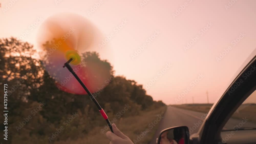 free girl waving a pinwheel out of the car window in wind, travel ...