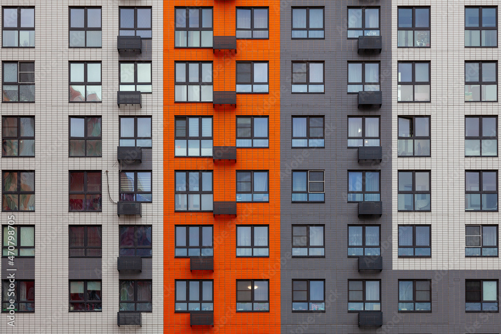Background image - a multi-colored wall of a multi-storey building with windows and balconies