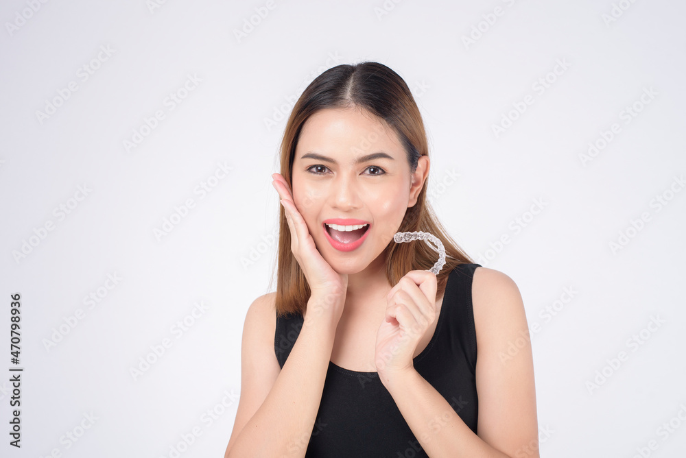 Young smiling woman holding invisalign braces in studio, dental healthcare and Orthodontic concept Young smiling woman holding invisalign braces in studio, dental healthcare and Orthodontic concept