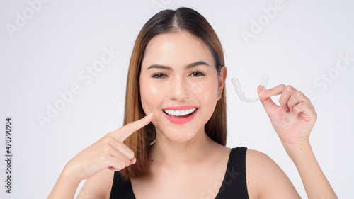 Young smiling woman holding invisalign braces in studio  dental healthcare and Orthodontic concept