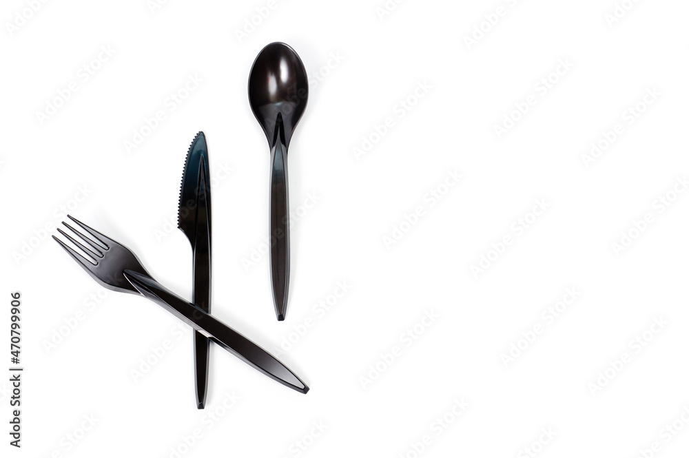 Fototapeta premium A set of plastic cutlery knife, fork and spoon in black, filmed on a white background