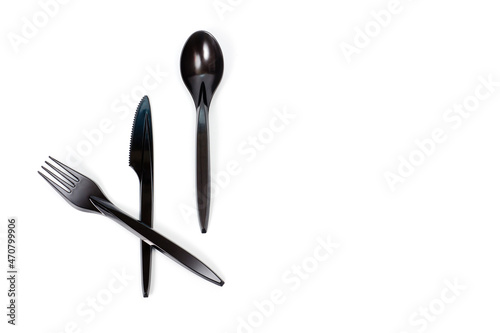 A set of plastic cutlery knife, fork and spoon in black, filmed on a white background