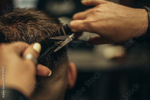 Young bearded man getting haircut by hairdresser