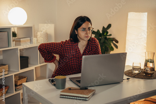 Beautiful woman having back and neck pain while using laptop at home © Zamrznuti tonovi