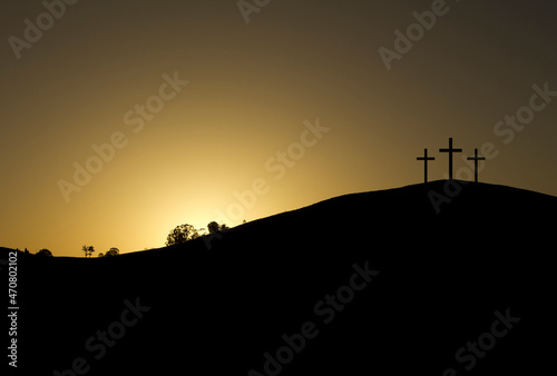 three crosses backlit on top of a mountain at sunrise with a golden sky. copy space, text space