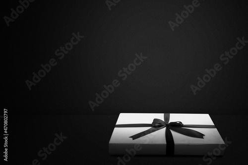 White gift box cap with a black ribbon with a black background photo