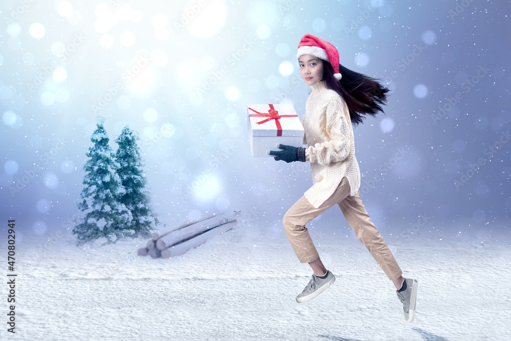 Asian woman with winter gloves and Santa hat holding white gift box
