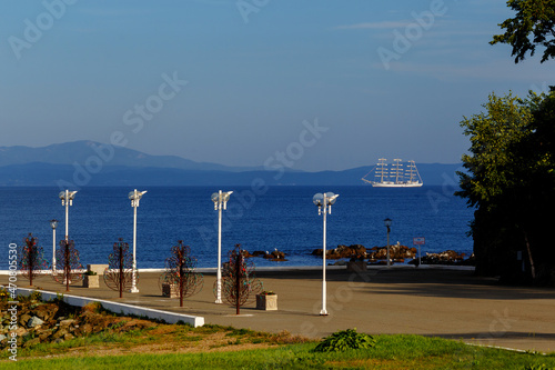 A white sailboat stands in the Sea of Japan near the coast. The training sailing ship Nadezhda is in the roadstead. photo