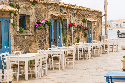 picturesque village of Marzamemi, in the province of Syracuse, Sicily - Tables and chairs setup in traditional Italian restaurants in the main square of the historic village during a sunny day. photo