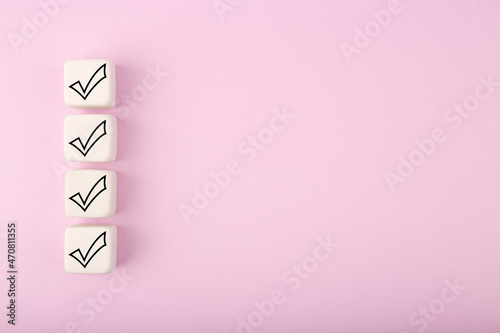 Four black checkmarks on white toy cubes in a row against bright pastel purple background with copy space. Concept of questionary, checklist, to do list, planning, business or verification. Modern min © Irina Ivanova