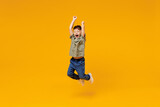 Full body overjoyed excited little small happy boy 6-7 years old wearing green t-shirt jump high with outstretched hands isolated on plain yellow background Mother's Day love family lifestyle concept