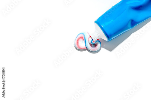 Dented blue tube with squeezed out toothpaste in white, red and blue lies on white background. Isolated. Copyspace