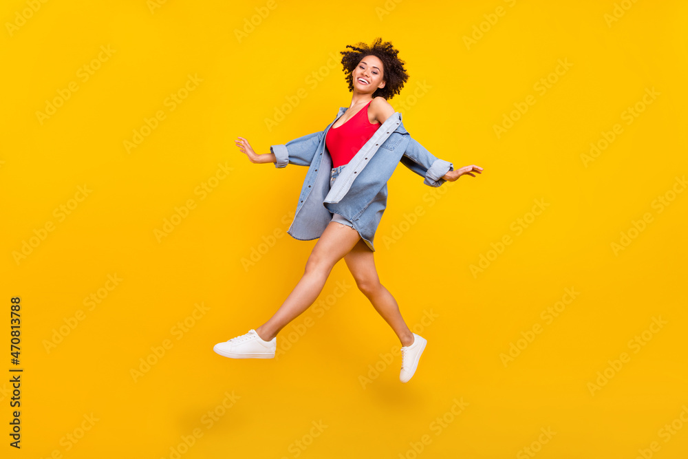Photo of carefree inspired lady jump enjoy flight wear denim jacket mini skirt shoes isolated yellow color background