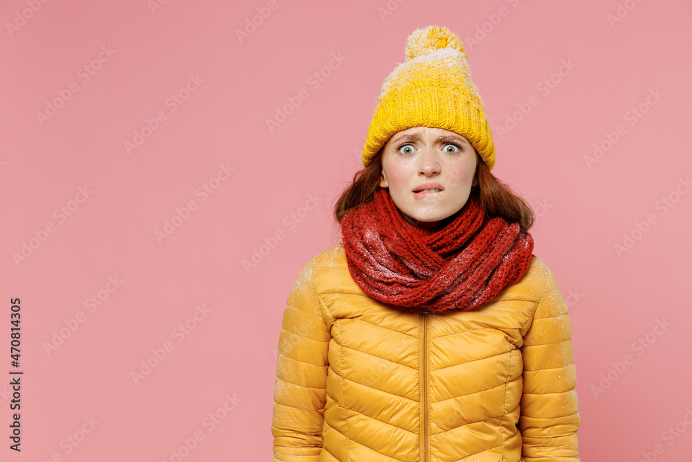 Impressed amazed panicked pop-eyed frightened scared young woman 20s years old wear ellow jacket hat mittens looking camera biting lips isolated on plain pastel light pink background studio portrait Impressed amazed panicked pop-eyed frightened scared young woman 20s years old wear ellow jacket hat mittens looking camera biting lips isolated on plain pastel light pink background studio portrait