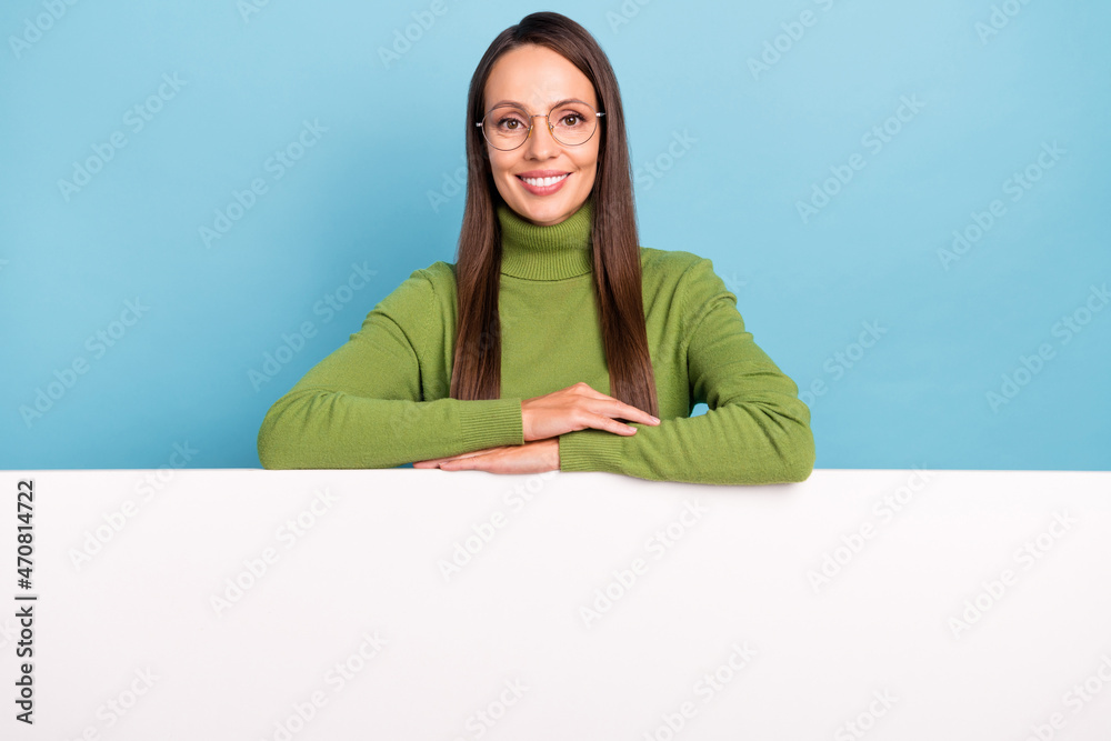 Photo of confident charming mature lady dressed green turtleneck spectacles holding empty space isolated blue color background Photo of confident charming mature lady dressed green turtleneck spectacles holding empty space isolated blue color background