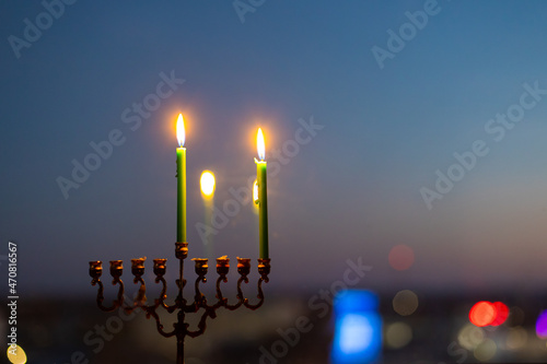 First day of Hanukkah. Light one candle in the menorah. Hannukia on the windowsill. Traditions of the religion of Judaism. The main holiday of the Jews. Sunset night