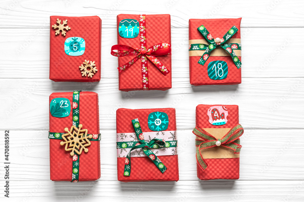Obraz premium Handmade wrapped red, green gift boxes decorated with ribbons, snowflakes and numbers, Christmas decorations and decor on white table Xmas advent calendar concept Top view Flat lay Holiday card