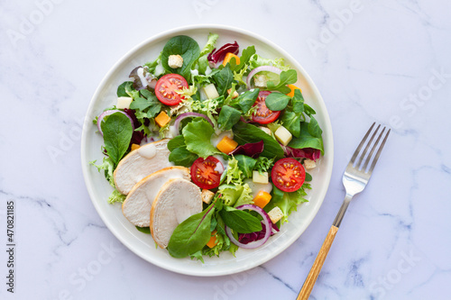 Caesar salad with chicken, lettuce, tomato, cheese and sauce on white background