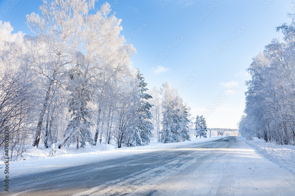 Winter road and snow-covered trees. Winter landscape with birch trees in the snow and a bright blue sky. Winter road and snow-covered trees. Winter landscape with birch trees in the snow and a bright blue sky.