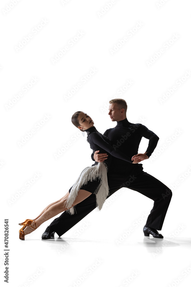 Dynamic portrait of young graceful dancers, flexible man and woman dancing ballroom dance isolated on white studio background.