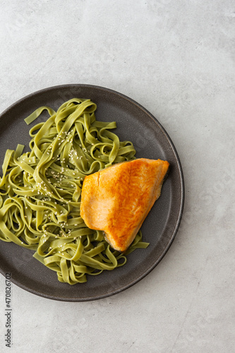 Green pasta tagliatelle with red fish Arctic char , top view of a plate with food, delicious healthy lunch
