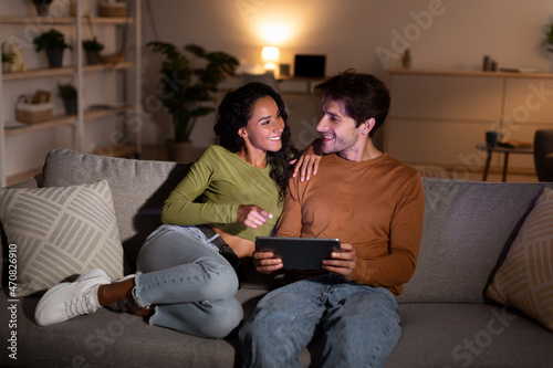 Cheerful Young Spouses Using Digital Tablet Together At Home