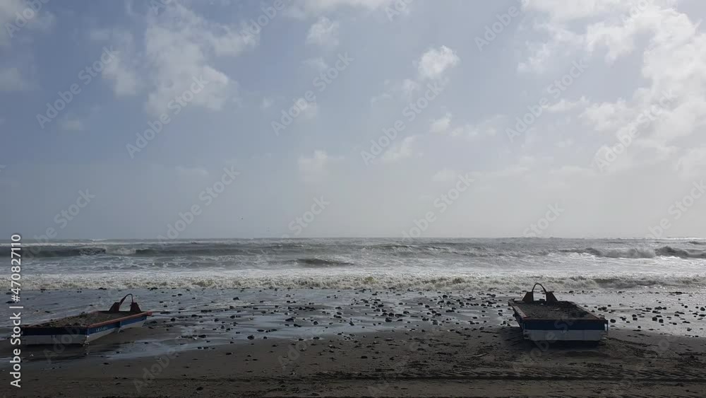 Strong waves due to the storm washing away sand and about to drag boats moored on the shore of the beach Strong waves due to the storm washing away sand and about to drag boats moored on the shore of the beach