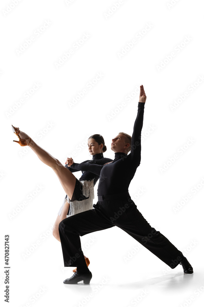 Dynamic portrait of young graceful dancers, flexible man and woman dancing ballroom dance isolated on white studio background.