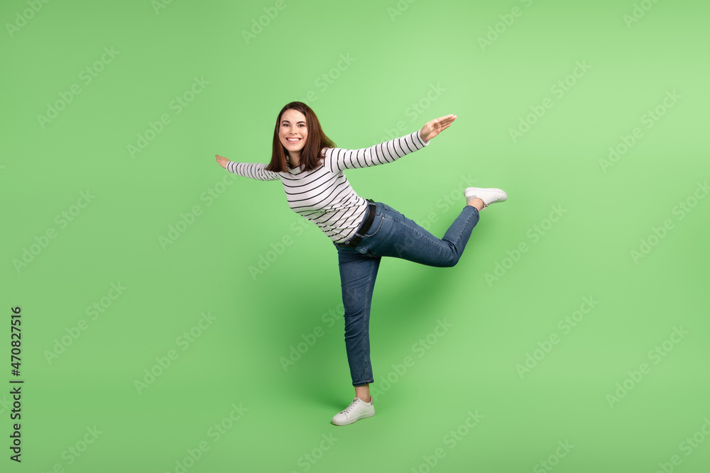 Full body profile side photo of young excited woman have fun fly air hands plane isolated over green color background Full body profile side photo of young excited woman have fun fly air hands plane isolated over green color background