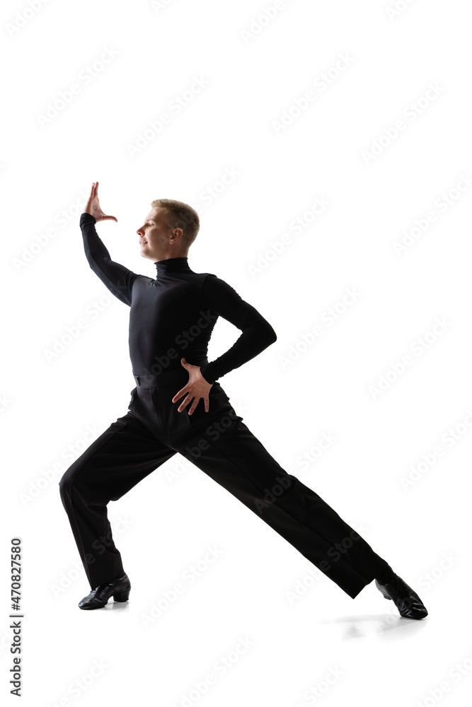 Portrait of young graceful male dancer, flexible man in black stage costume dancing ballroom dance isolated on white studio background.