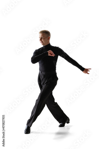 Portrait of young graceful male dancer, flexible man in black stage costume dancing ballroom dance isolated on white studio background.