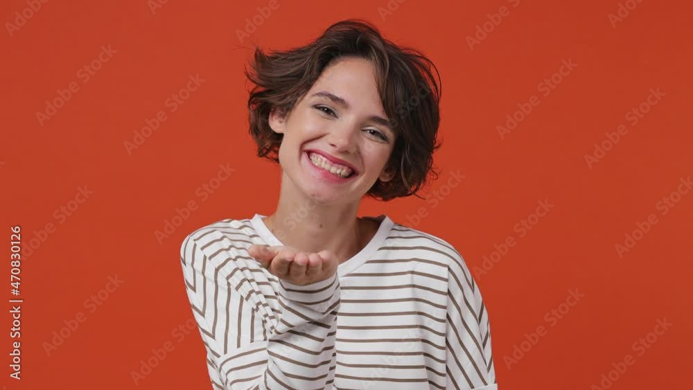 Coquette fascinating charming marvelous magnificent beautiful vivid young brunette woman 20s years old wears striped shirt blowing sending air kiss isolated on plain orange background studio portrait