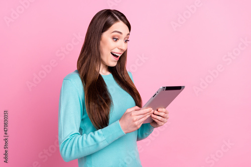 Photo of adorable impressed young woman wear blue sweater typing modern gadget smiling isolated pink color background