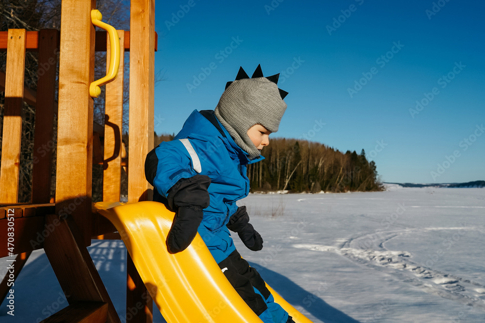 Boy on the playground in winter day.