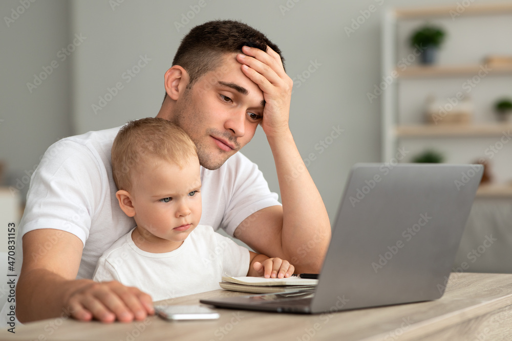 Tired Father With Little Baby Trying To Work On Laptop At Home Tired Father With Little Baby Trying To Work On Laptop At Home