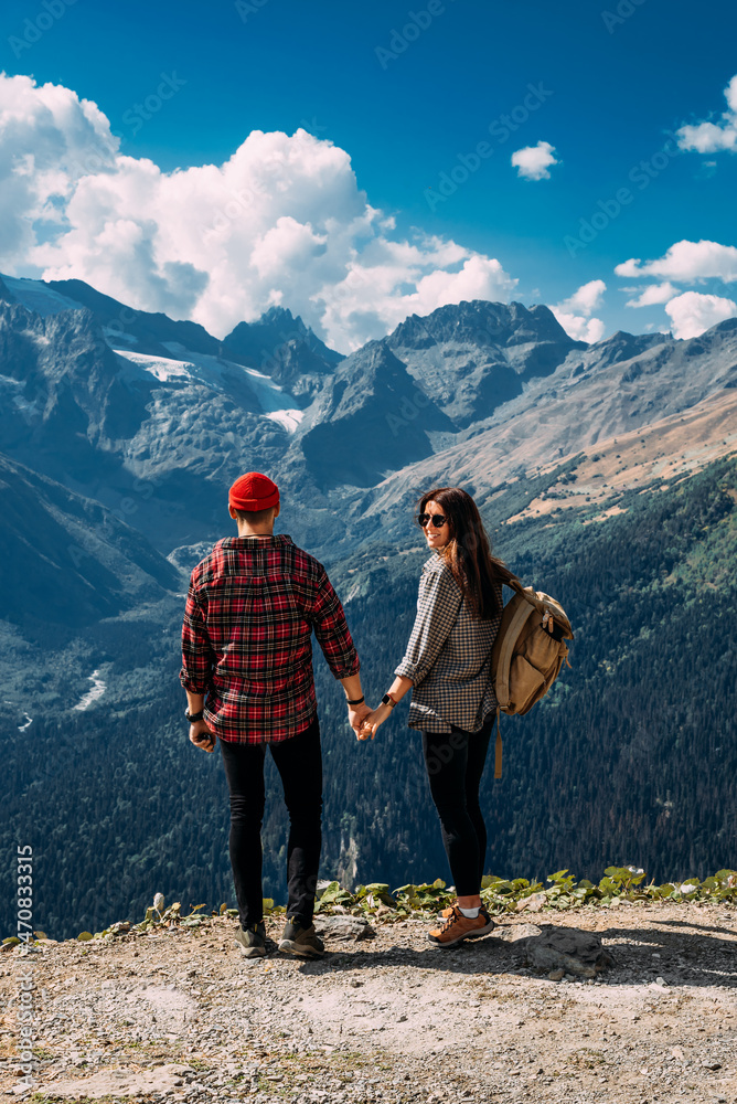 A couple in love on a rock admires the beautiful views. A man and a woman on a rock. A couple in love travels. A man and a woman in the Caucasus mountains. Couple traveling through the mountains