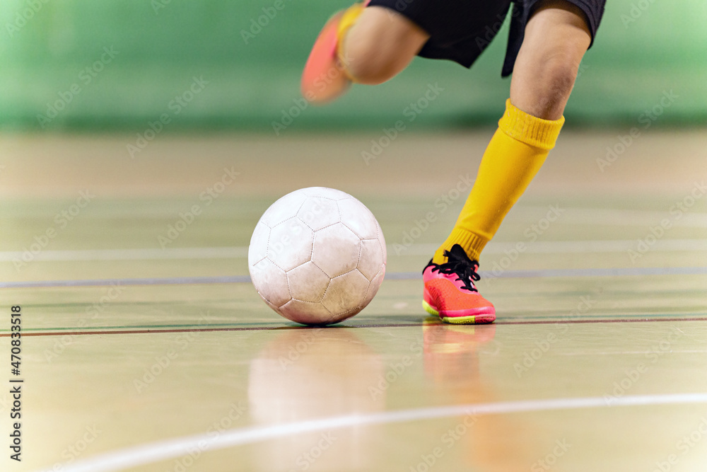 Fototapeta premium Close-up Image of Futsal Player Kicking Ball. Indoor Soccer Ball Kick. Indoor Football Equipment. Junior Footballer Running and Kicking Ball