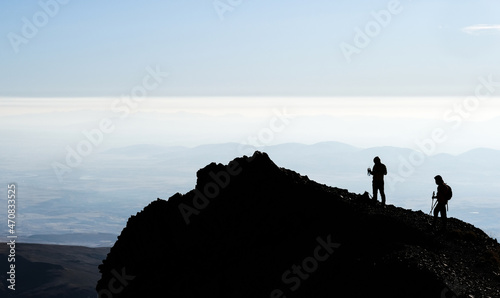 Silhouette of hikers on mountain top on clear sky background photo