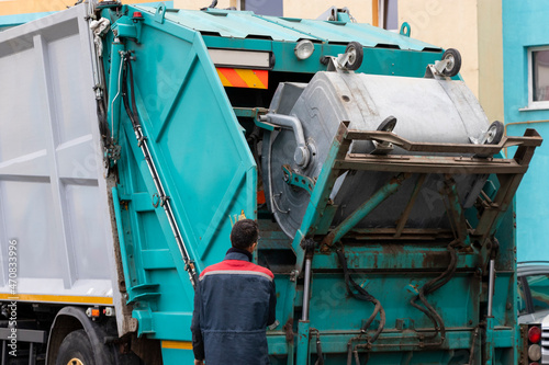 A garbage truck picks up garbage in a residential area. Workers load a container with garbage. Separate collection and disposal of garbage.