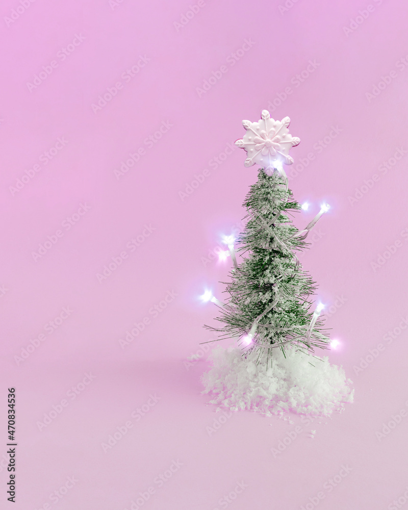Minimal New Year’s arrangement with Christmas lights, Christmas tree, artificial snow and homemade cookie in the shape of a snowflake, against pastel pink background. Decorative greeting card idea. Minimal New Year’s arrangement with Christmas lights, Christmas tree, artificial snow and homemade cookie in the shape of a snowflake, against pastel pink background. Decorative greeting card idea.